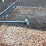 This is a photo of a floral rug that is being steam cleaned. The bottom half has been completed and the top half is being done works carried out by Chigwell Carpet Cleaning