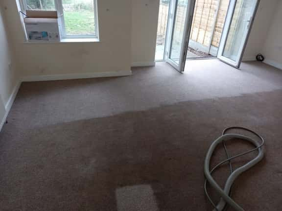 This is a photo of an empty living room with a brown carpet that is in the process of having its carpets steam cleaned works carried out by Chigwell Carpet Cleaning