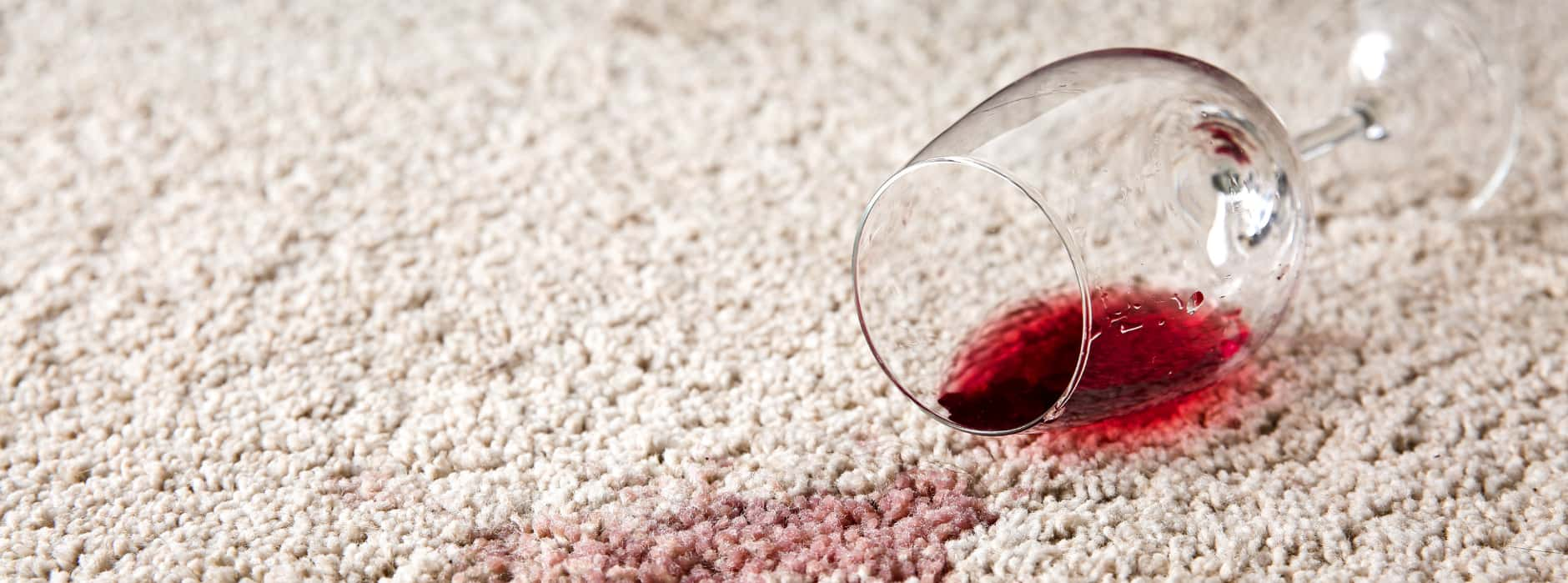 This is a photo of Chigwell Carpet Cleaning red wine which has been spilt on a cream carpet. The glass is on its side.